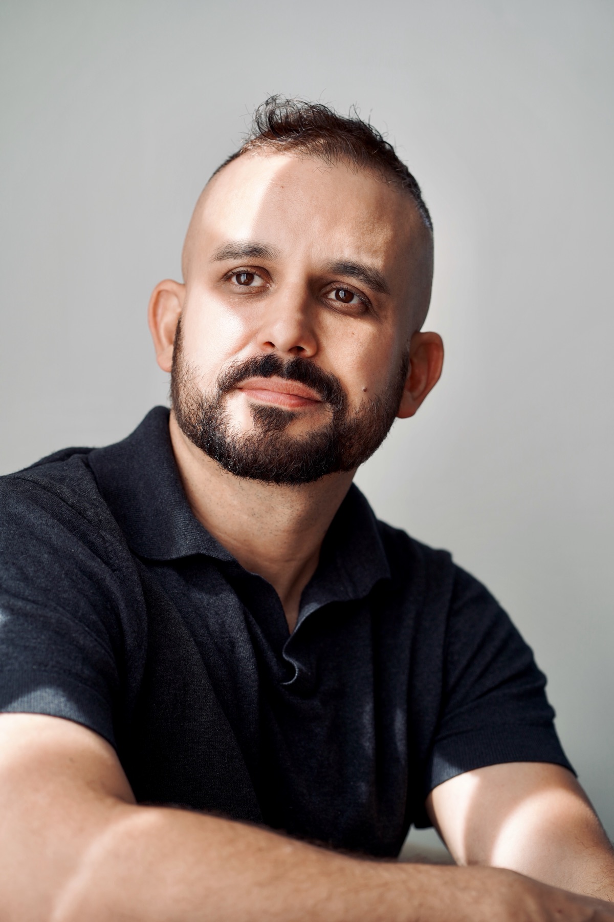 Portrait in a black polo, arms crossed, studio light